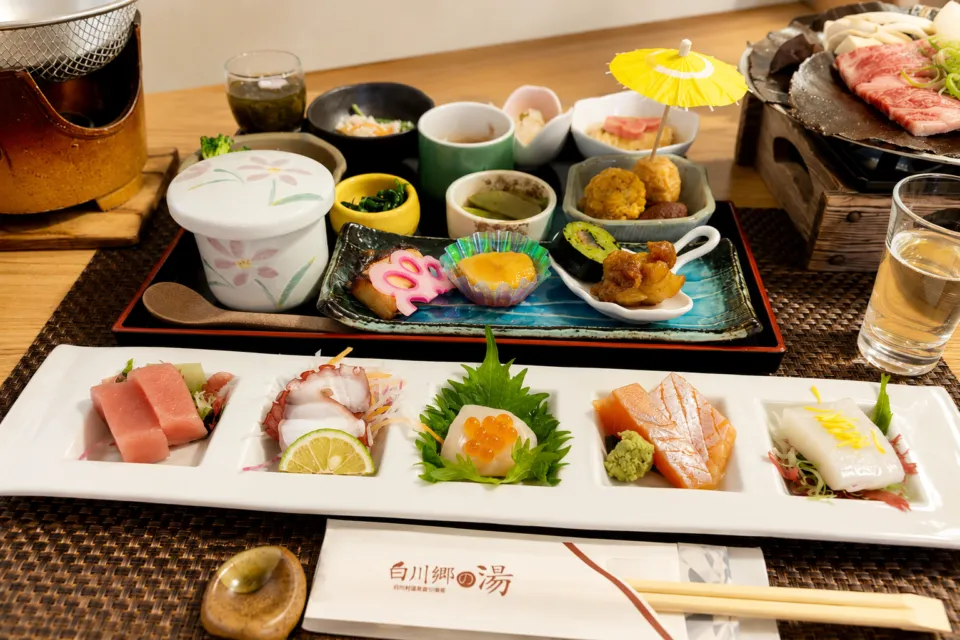 天然温泉白川郷の湯の刺身と卓上鍋を並べた食事