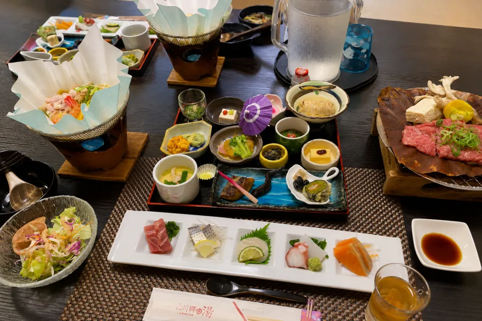 天然温泉白川郷の湯の刺身や鍋料理を並べた夕食