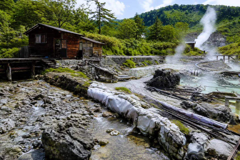 玉川温泉の湯けむり立つ源泉地と小屋