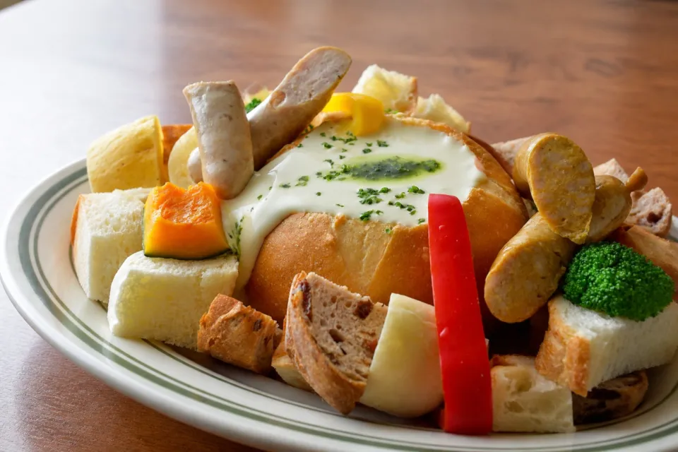 ベーカリー ペニーレイン 那須店のパンの器にチーズを入れソーセージや野菜を添えた料理