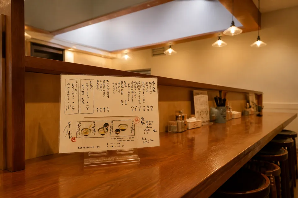 堂の浦 駅前店の木のカウンターに置かれたメニュー案内