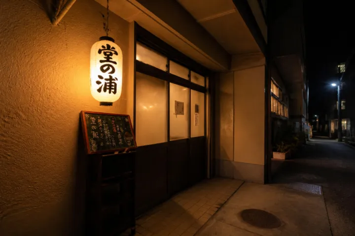 堂の浦 駅前店の夜の入口と店名入りの提灯