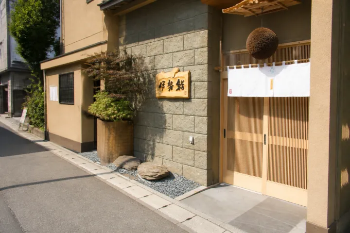 伊勢鮨の暖簾と木製看板がある店舗外観