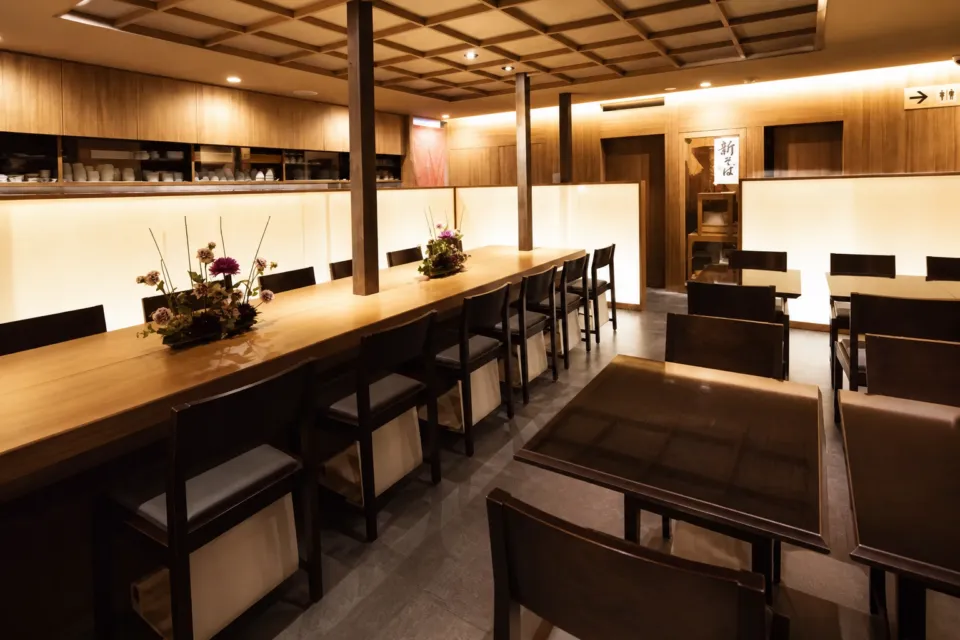 石臼挽蕎麦 三國家の長い木製カウンターとテーブル席が見える三國家の店内