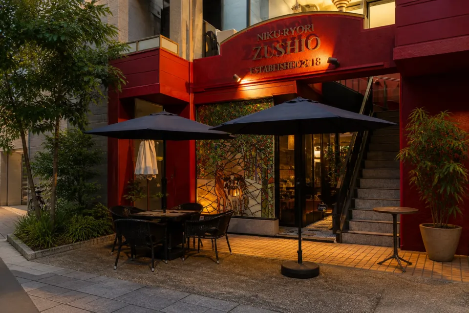 肉料理 Zushioの看板が見える店舗外観とテラス席
