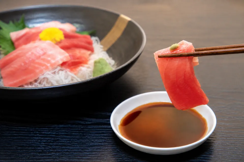 お料理 七草の箸で持ち上げたまぐろの刺身