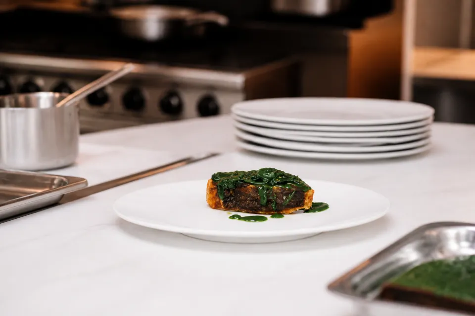 オトワレストランの厨房でソースを仕上げる肉料理