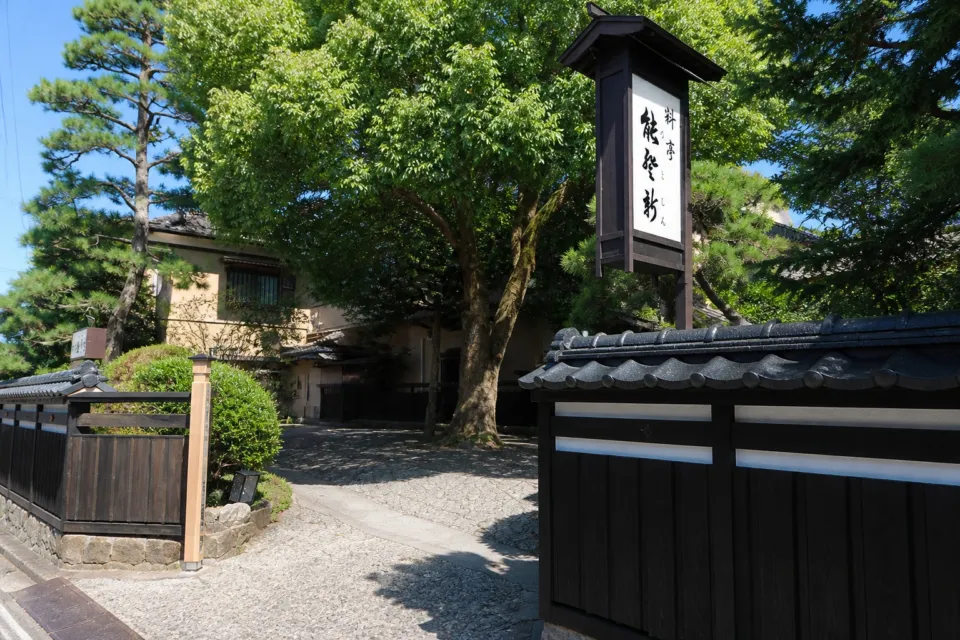 料亭 能登新の料亭 能登新の黒塀と看板が見える外観