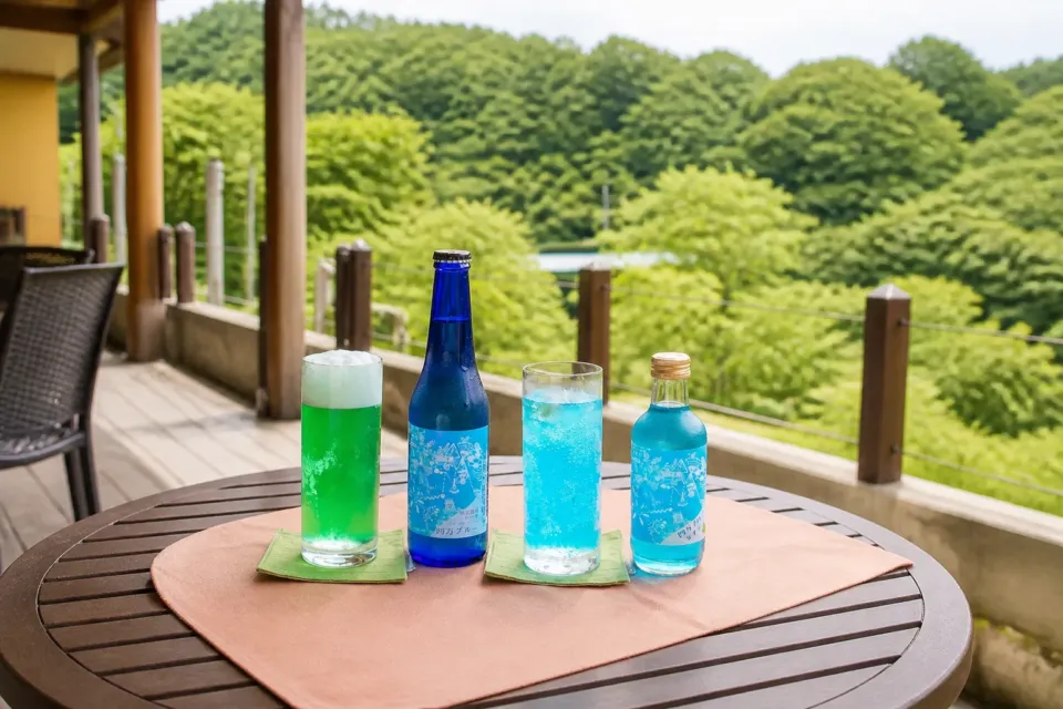 シマテラスの緑を背景にした四万ブルーのドリンクとボトル