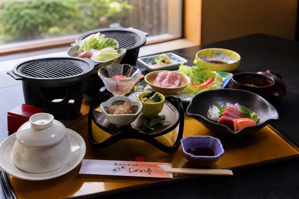 奥州平泉温泉 そば庵 しづか亭の刺身や鍋物を並べた夕食膳