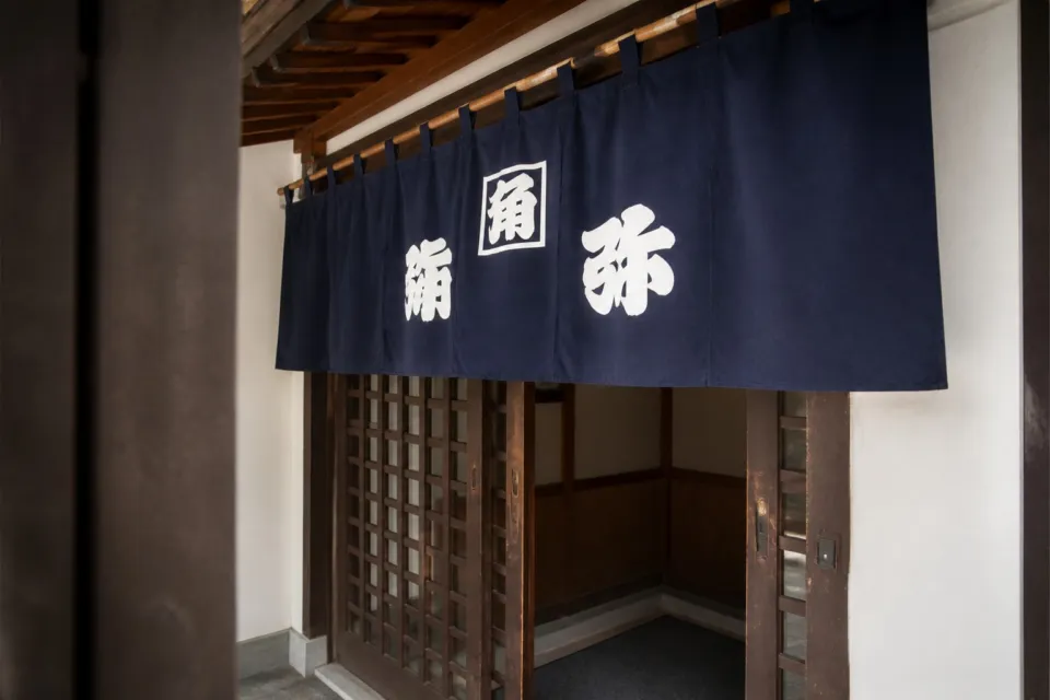 そば処 角弥の山並みと暖簾が見える入口まわり