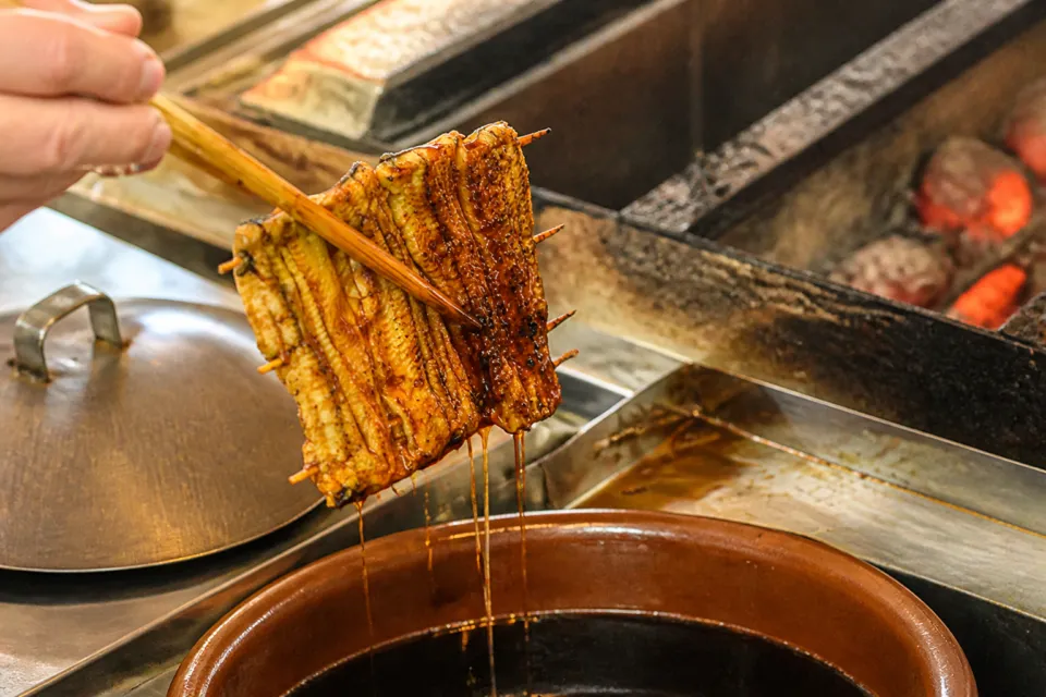 魚登久の蒲焼をタレにくぐらせる工程