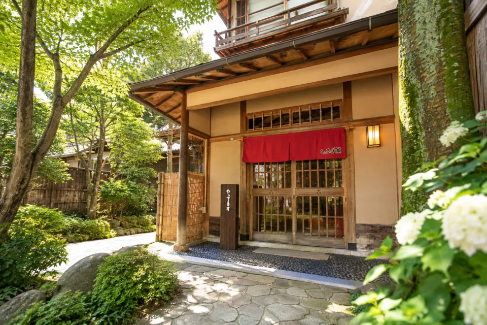 あり釜めし くつろぎ家の赤いのれんと木の引き戸の店舗入口