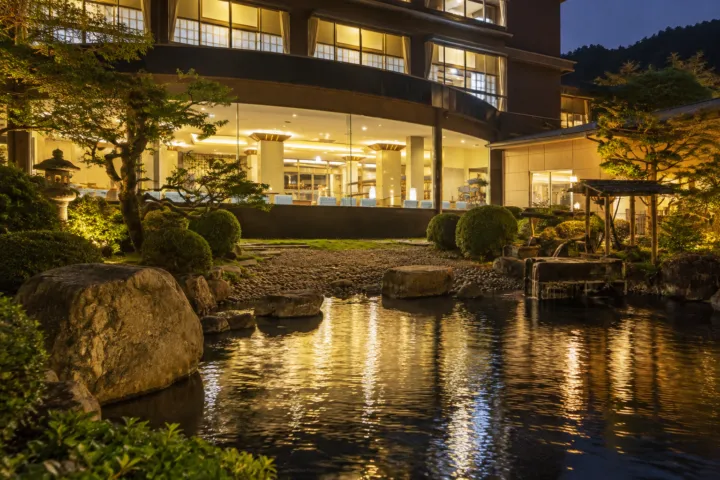 望川館の池越しに見る夕方の建物外観