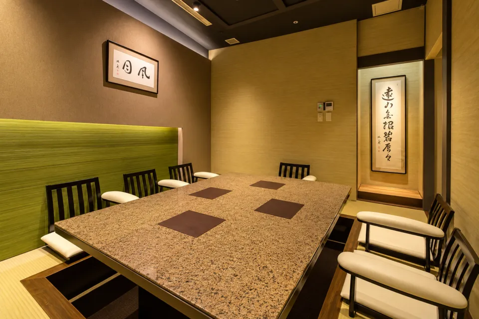 伊達の牛たん本舗 本店の緑の壁面と長テーブルを備えた個室
