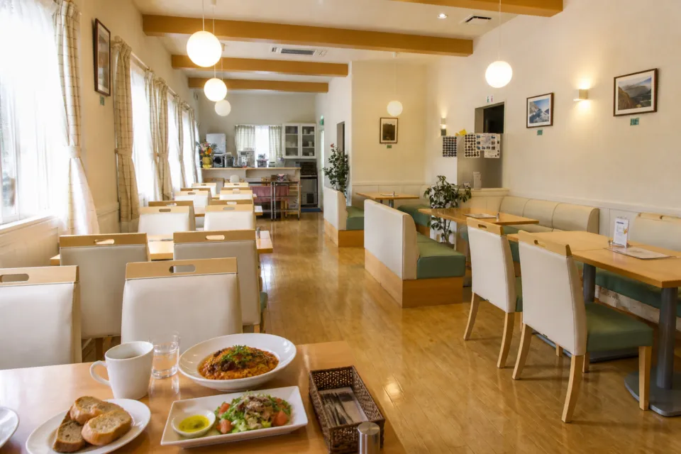 お山のカフェレストラン グリーンテラス雲仙の木のテーブルと白い椅子が並ぶ明るい店内