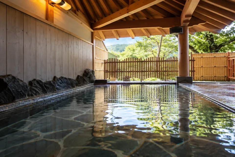 楊貴妃浪漫の宿 玉仙閣の木の屋根と石の浴槽を備えた露天風呂