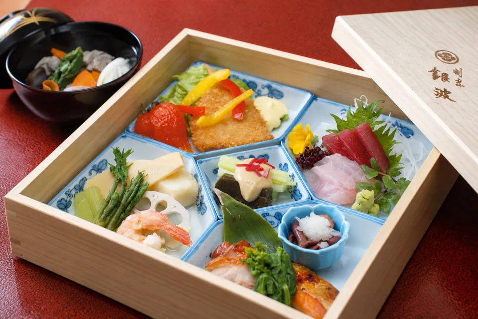 割烹 銀波の木箱に彩りよく詰めた昼の弁当