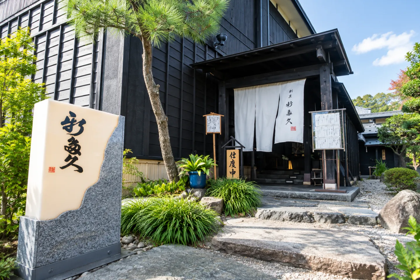 割烹 新多久の暖簾と店名碑がある玄関