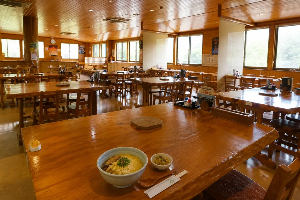 鶏飯の店 ひさ倉の広い店内に木製テーブルと椅子が並ぶテーブル席