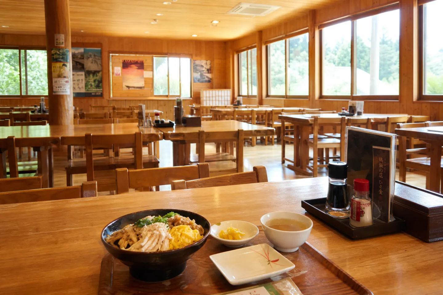 鶏飯の店 ひさ倉の窓際まで広がる明るい食堂で食事を楽しむ人々