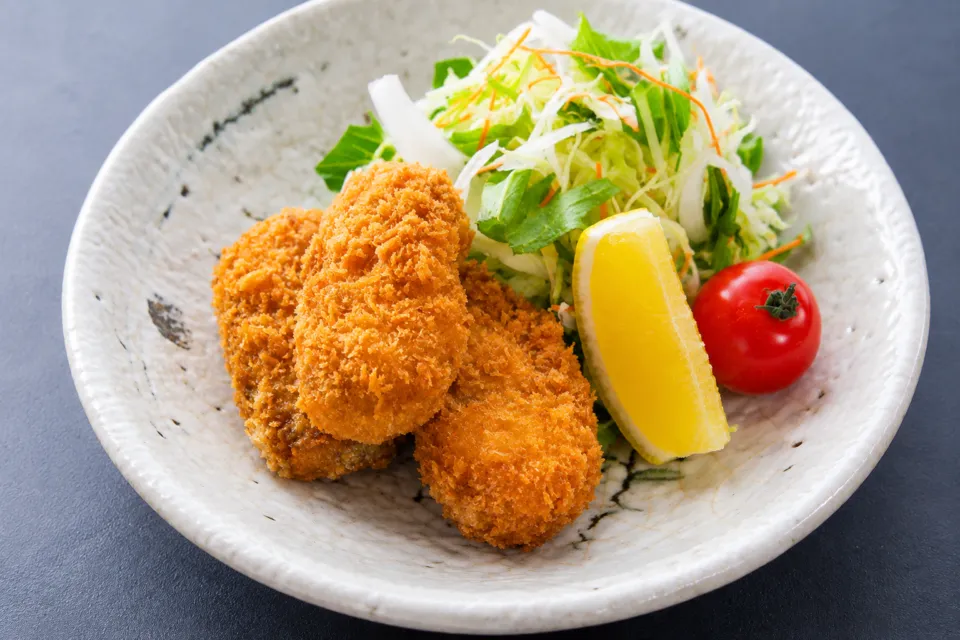かきと海鮮料理 旬海の牡蠣フライと野菜を盛った皿