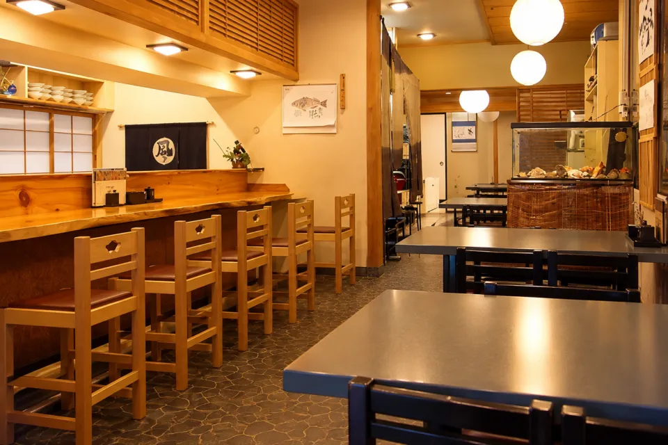 かきと海鮮料理 旬海のカウンターと丸い照明が見えるテーブル席の店内