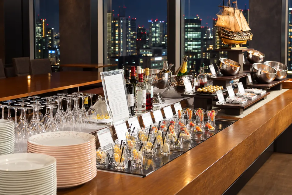 名古屋プリンスホテル スカイタワーの夜景を背に料理や飲み物が並ぶクラブラウンジ