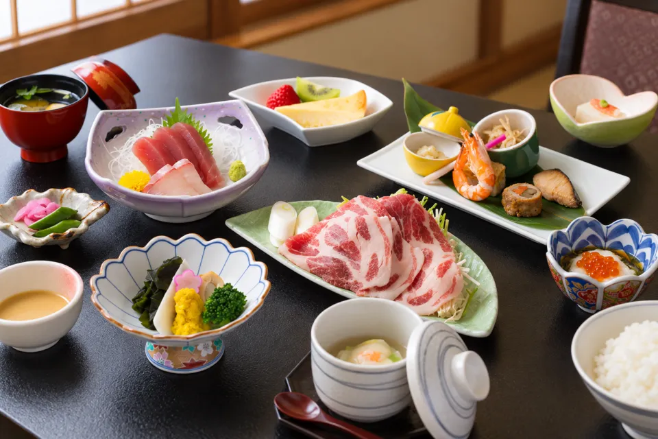 鉛温泉 藤三旅館の肉料理と小鉢を並べた食事