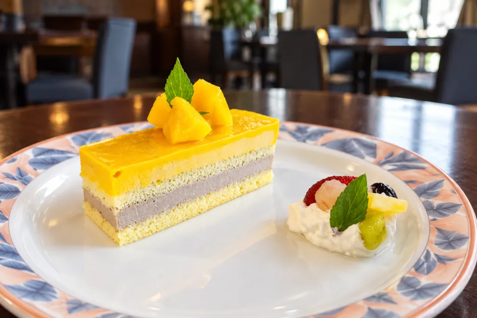 レストラン＆カフェ浪漫座の黄色の層があるケーキと果物の皿