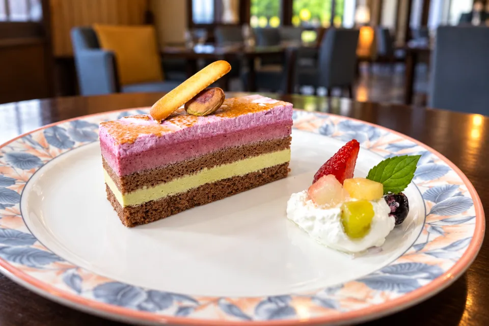 レストラン＆カフェ浪漫座の紫色の層があるケーキと果物の皿