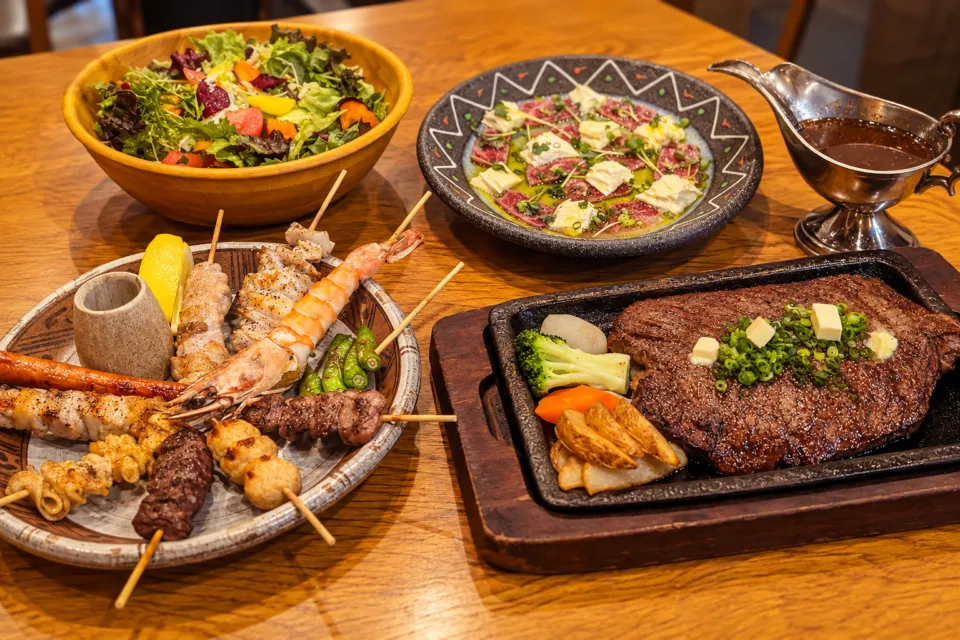 Restaurant Nikko えんやの串焼きとステーキを並べた食卓