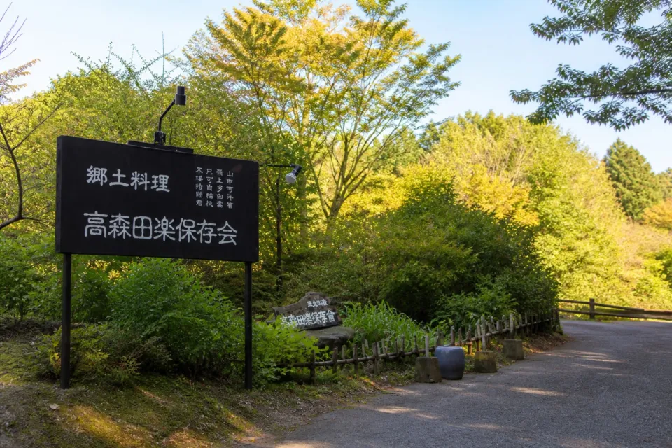 高森田楽保存会の木立の中に立つ店舗看板