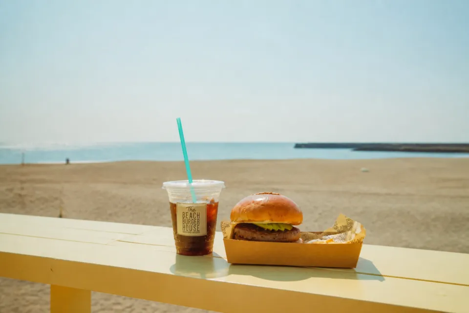The BEACH BURGER HOUSEの海を背景に置かれたハンバーガーとドリンク
