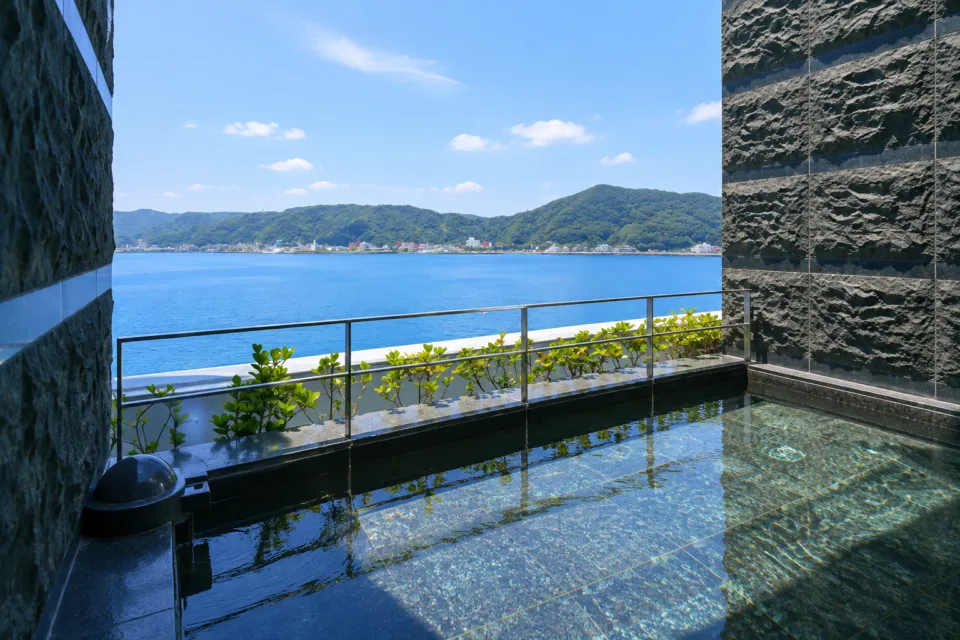奄美山羊島ホテルの露天風呂の浴槽越しに見える海と山並み