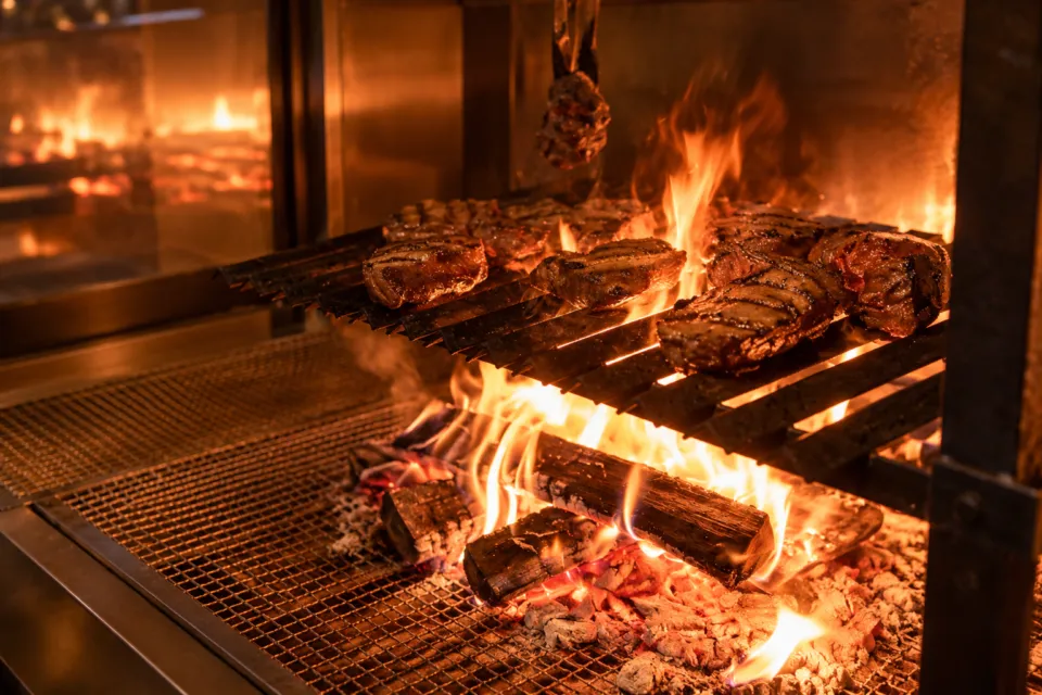 オーベルジュ内子の炎を上げる薪火と焼き網の肉