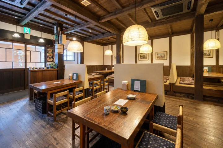 村上牛専門料理店 江戸庄の木の梁とテーブル席の店内