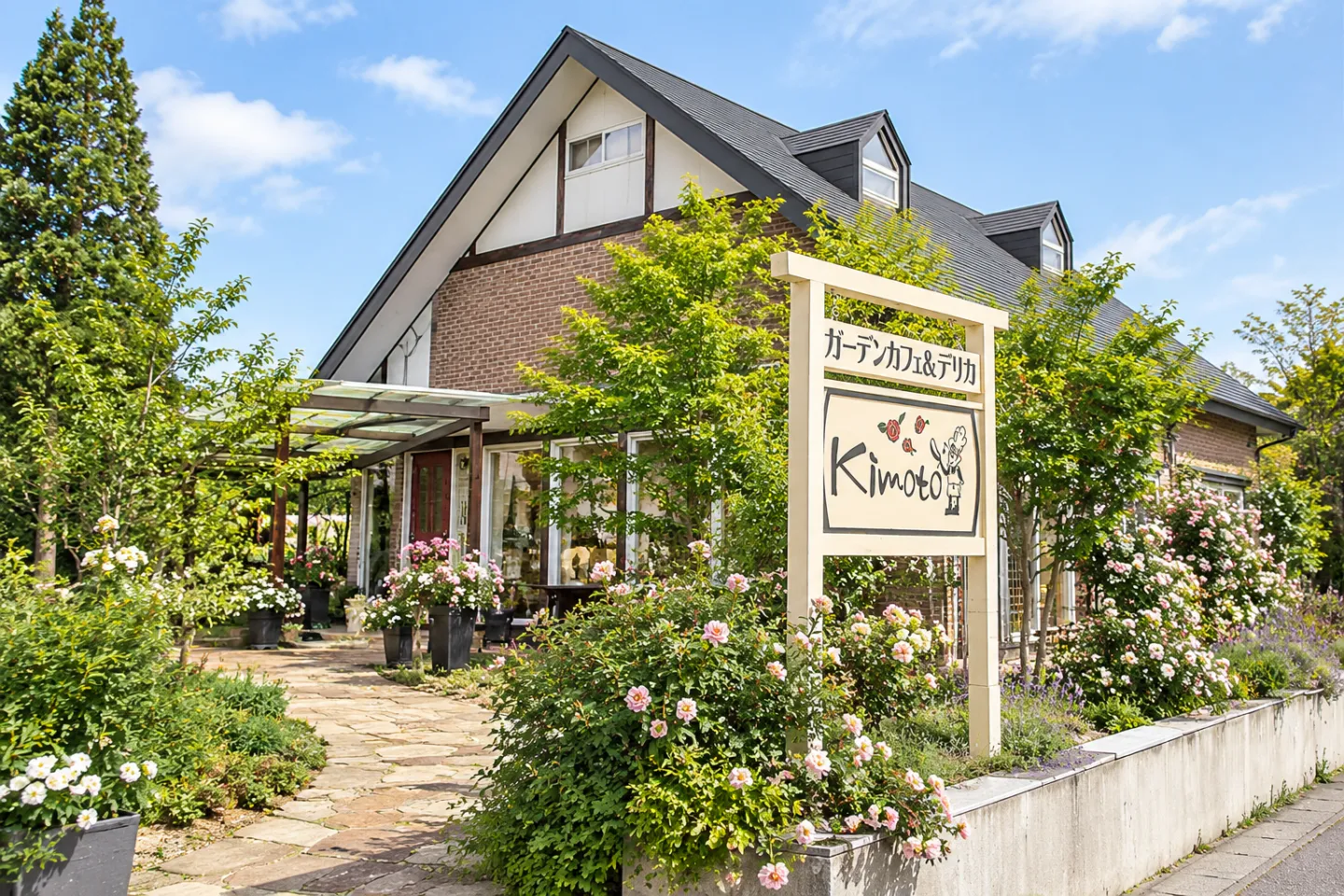 ガーデンカフェ＆デリカテッセンkimotoの緑の屋根と花に囲まれた店舗外観