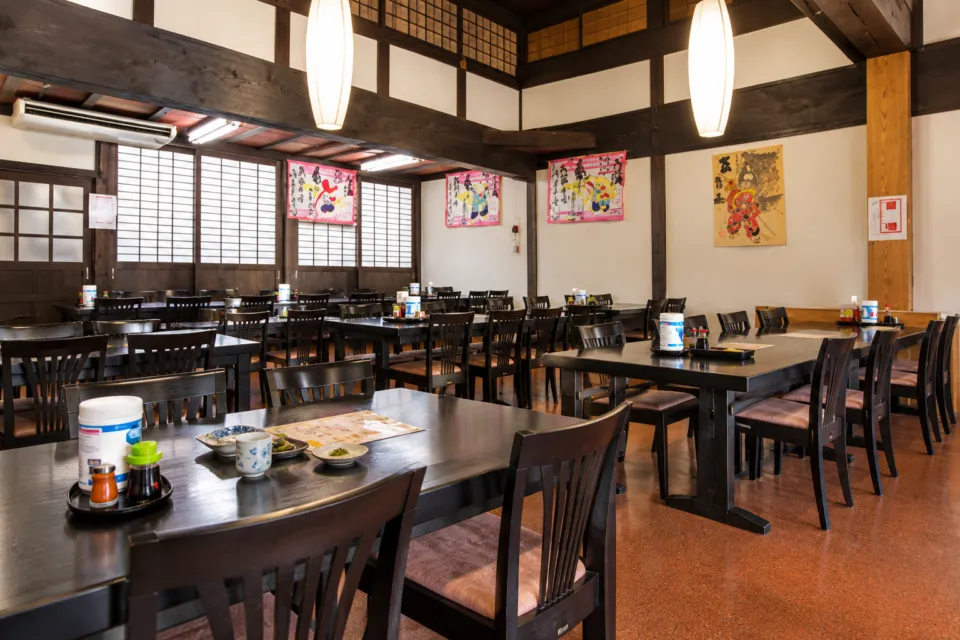 五箇山の味 ふるさとの木の梁とテーブル席が並ぶ店内