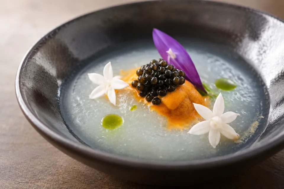 Kaji synergy restaurantの白い花と黒い粒を添えた料理