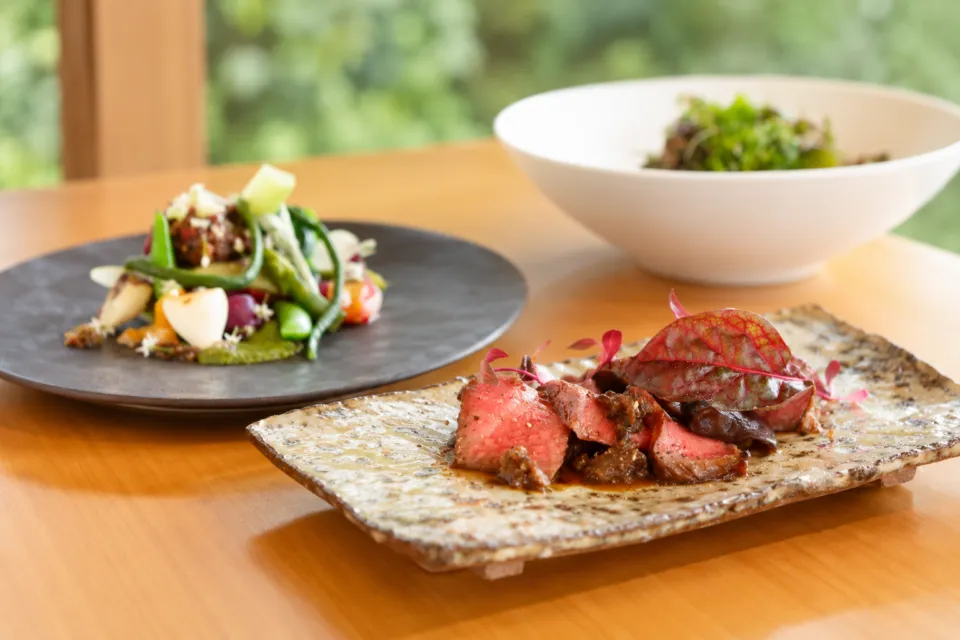 Kaji synergy restaurantの肉と野菜の料理を並べた食卓