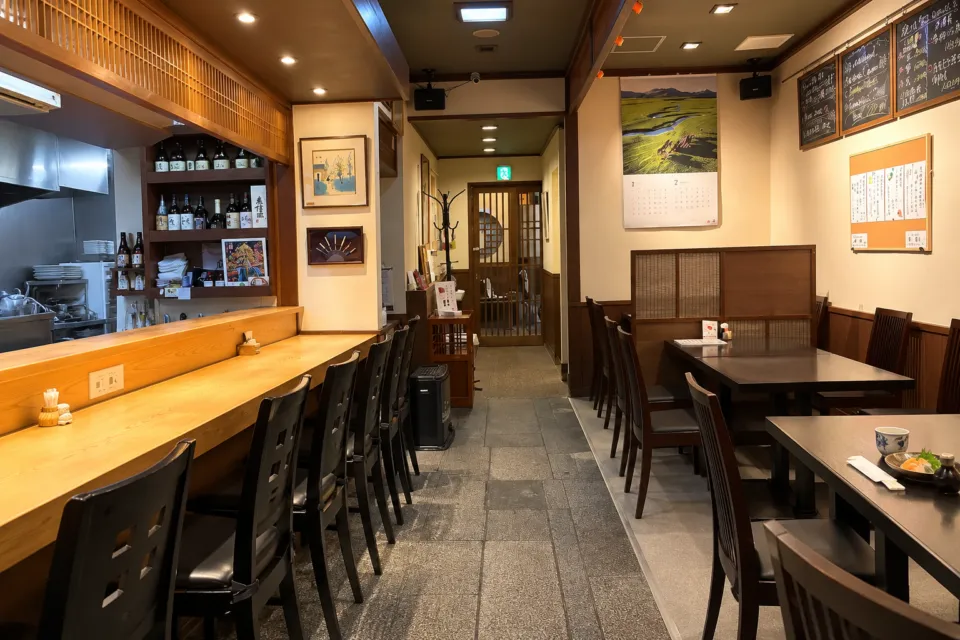 割烹 千渡里の仕切りのある椅子席とカウンターが見える店内