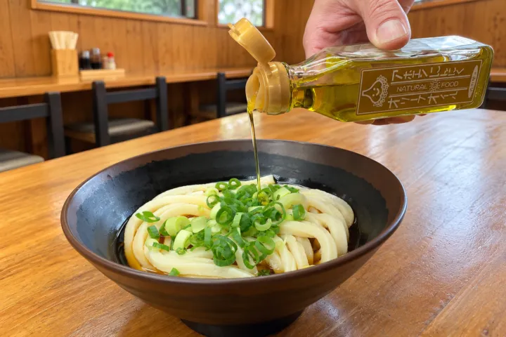 木の崎うどん 直島店の店内の卓上でオイルを注ぐあほうどん