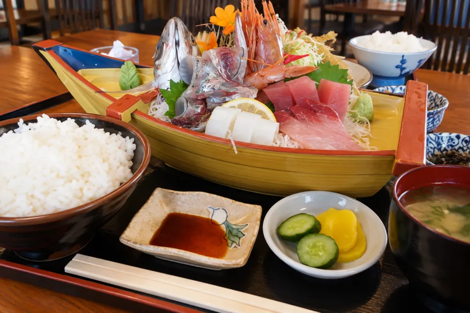 まるよ 西条店の舟形の器に盛られた刺身とご飯の食卓