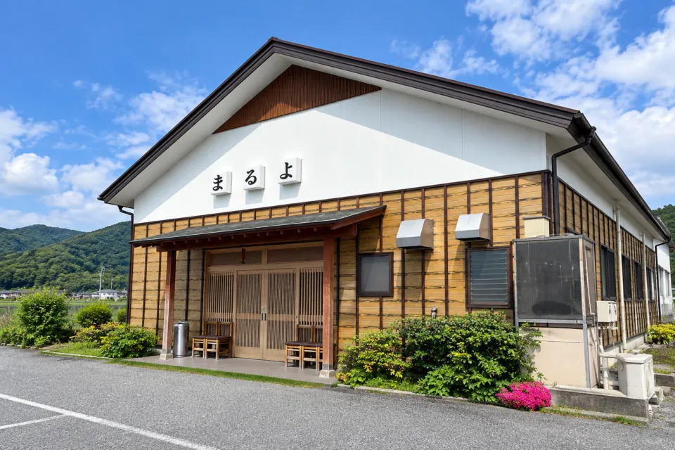 まるよ 西条店の木張り外壁と玄関が見える外観