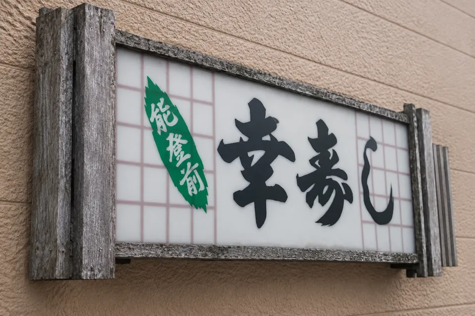 能登前幸寿しの壁面の店舗看板