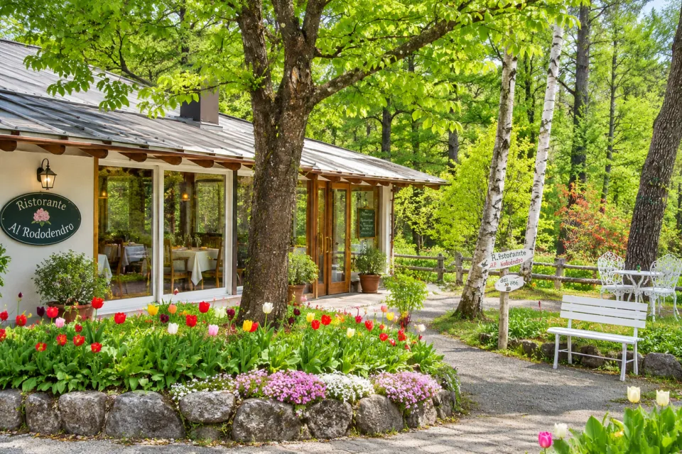 リストランテ アル・ロドデンドロの緑に囲まれた建物と店名看板