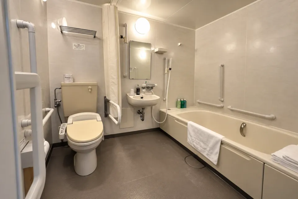 ホテルルートイン石巻河南インターの浴槽と手すり、洗面台、トイレがあるバリアフリー客室の浴室