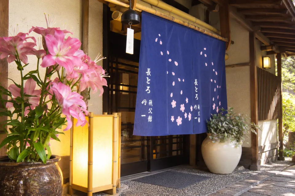 鮎料理の丹一の桜模様の暖簾と花が飾られた入口