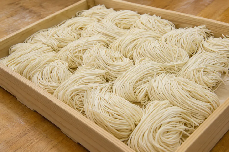 釜揚げうどん 戸隠 本店の木の台にまとめられた細いうどんの生麺